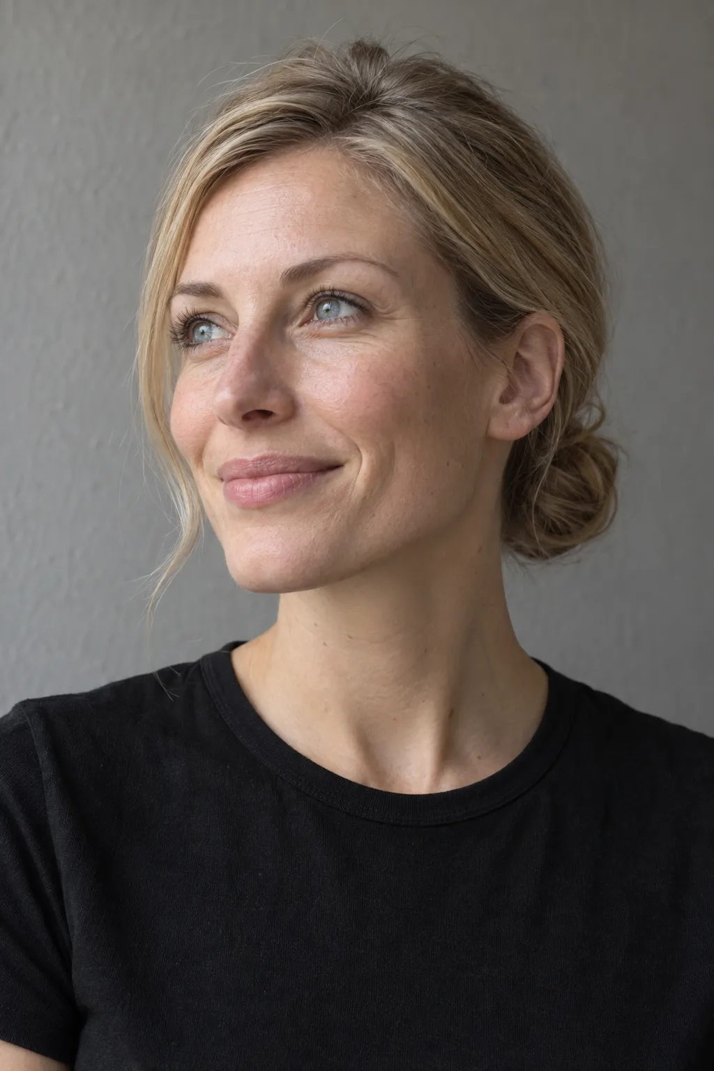 Blonde model with a low bun and a thoughtful smile